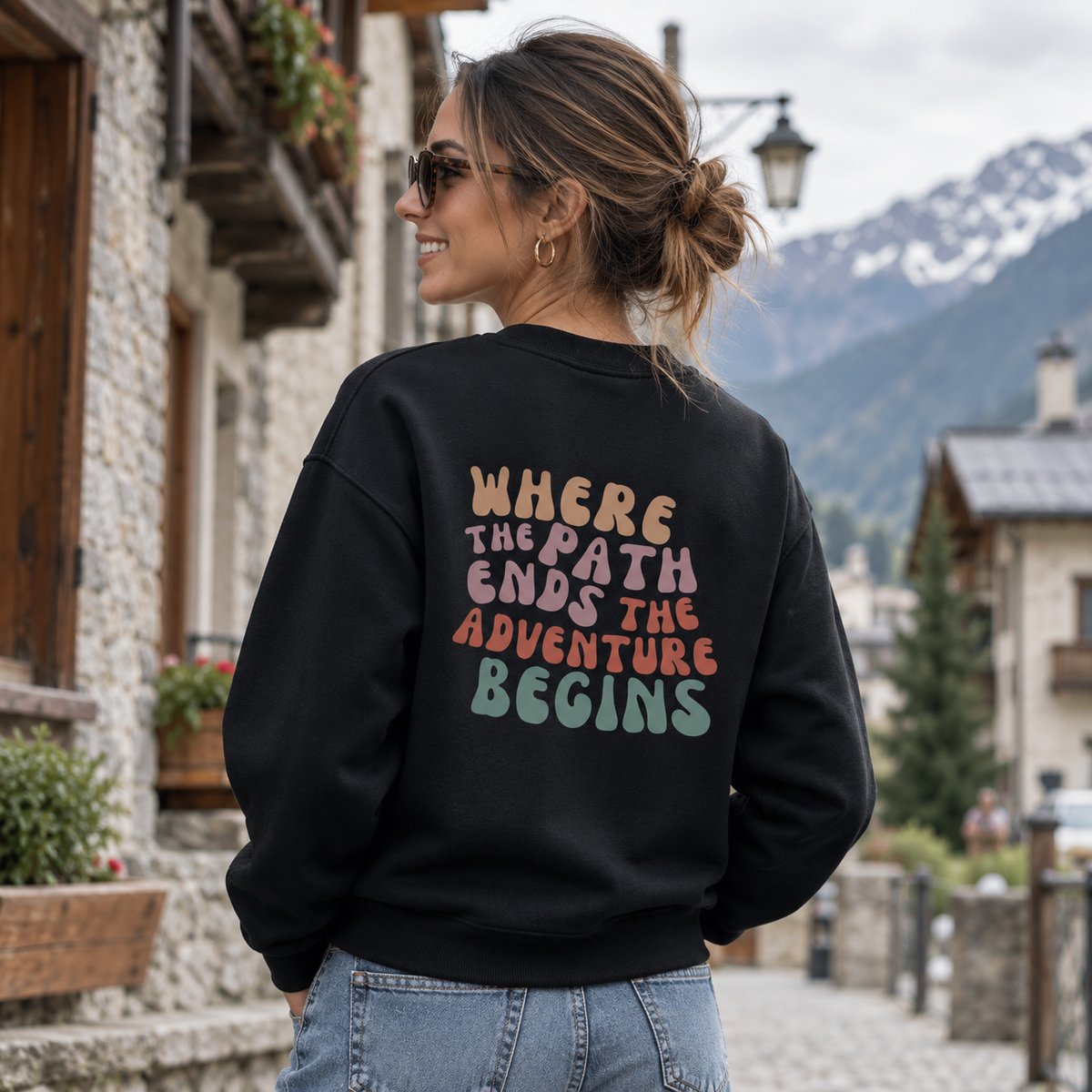 Frau im schwarzen Trailrunning Sweatshirt in einem realistischen alpinen Streetwear-Setting