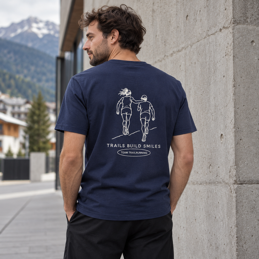Mann trägt das Trails Build Smiles Bio Premium T-Shirt mit großem Backprint in einem urbanen Outdoor-Streetwear-Setup