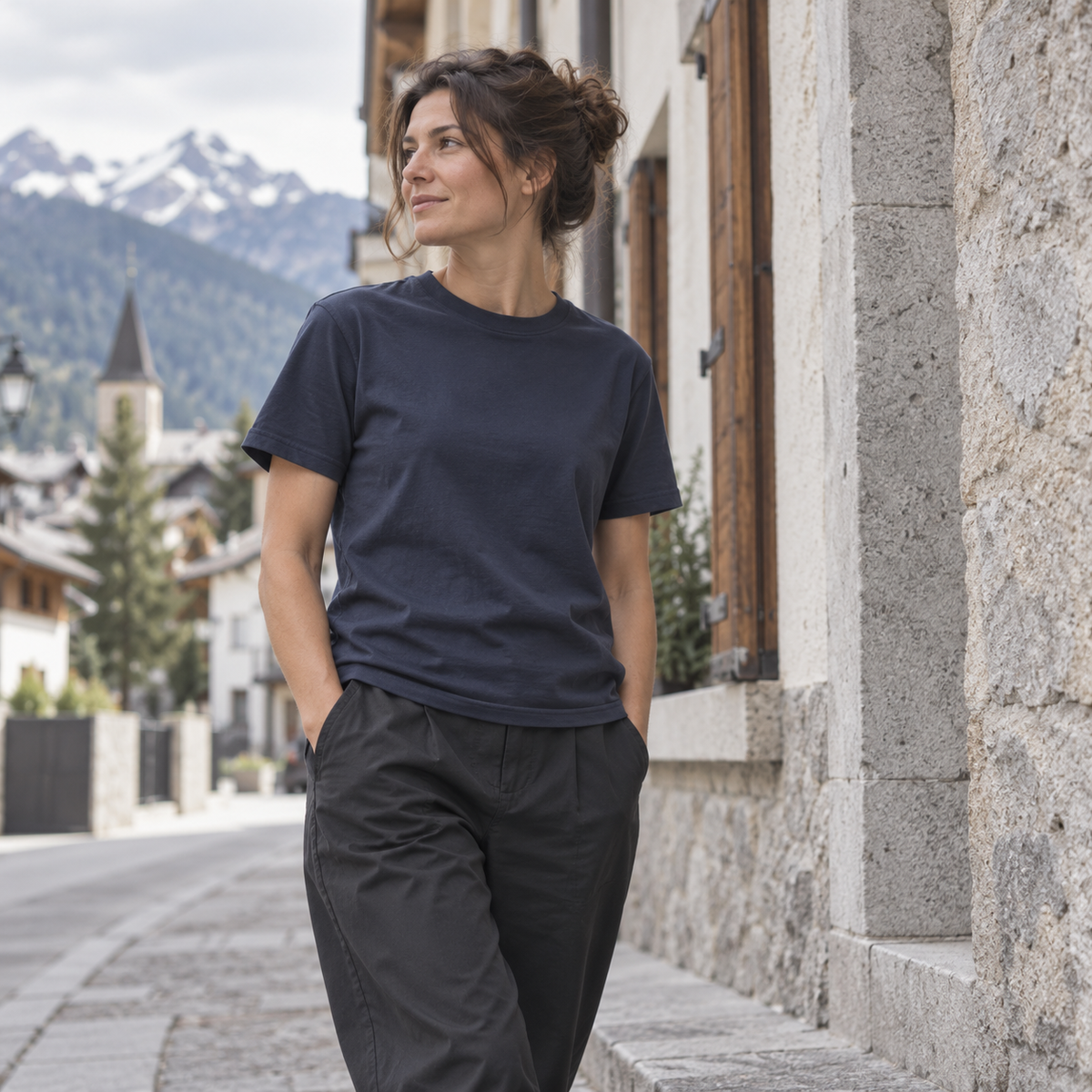 Frau im dunkelblauen Bio-T-Shirt in einer alpinen Stadt